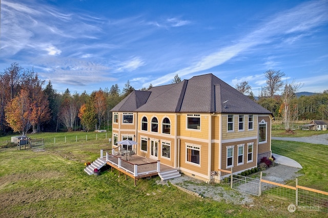 rear view of property featuring a deck and a lawn