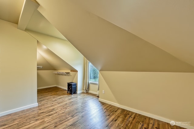 additional living space with hardwood / wood-style floors and vaulted ceiling