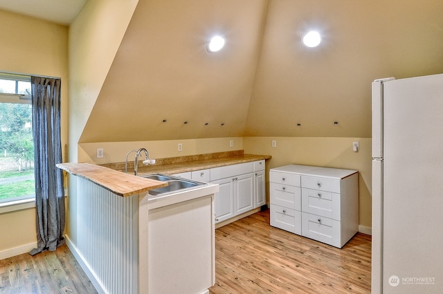 kitchen featuring lofted ceiling, white refrigerator, white cabinetry, light hardwood / wood-style floors, and butcher block countertops