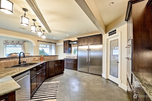 kitchen featuring dark brown cabinets, light stone countertops, stainless steel appliances, sink, and decorative light fixtures