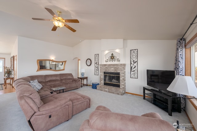 carpeted living room with vaulted ceiling, a brick fireplace, and ceiling fan