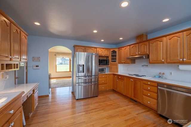 kitchen featuring decorative backsplash, appliances with stainless steel finishes, tile counters, and light wood-type flooring