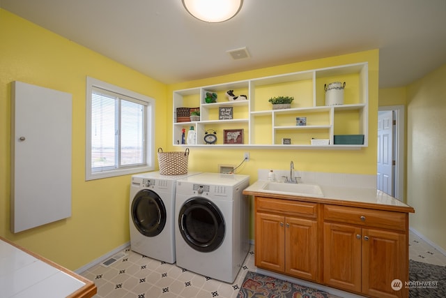 laundry area with sink, washing machine and dryer, and cabinets