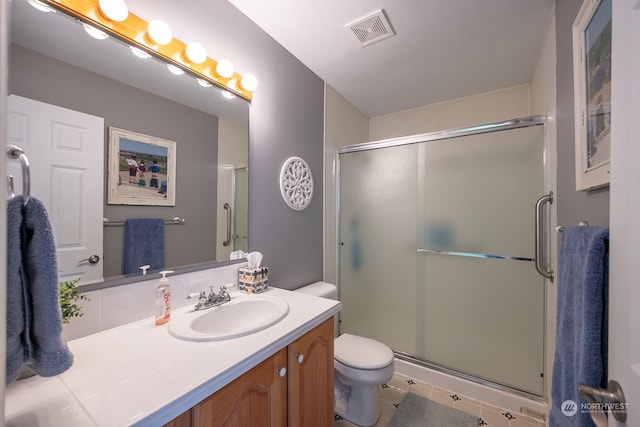 bathroom featuring vanity, an enclosed shower, toilet, and tile patterned flooring