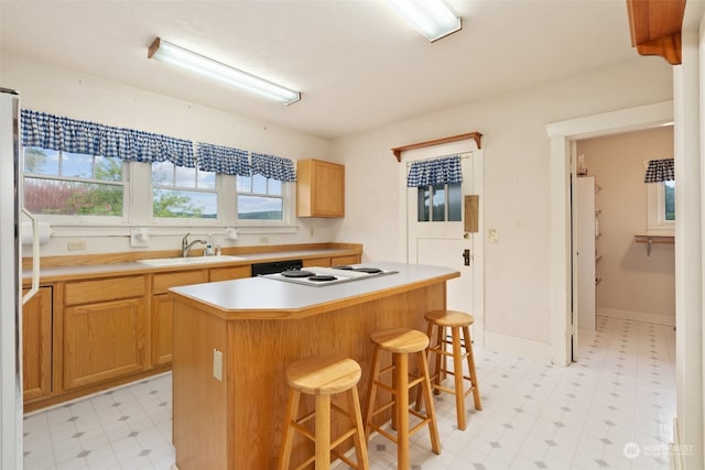 kitchen featuring a breakfast bar area, white gas stovetop, sink, and a center island