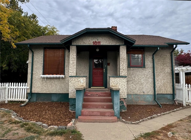 bungalow-style home featuring stucco siding and fence