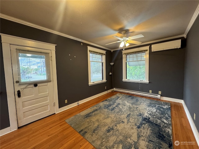 foyer featuring ceiling fan, ornamental molding, a wall mounted air conditioner, a baseboard heating unit, and hardwood / wood-style flooring