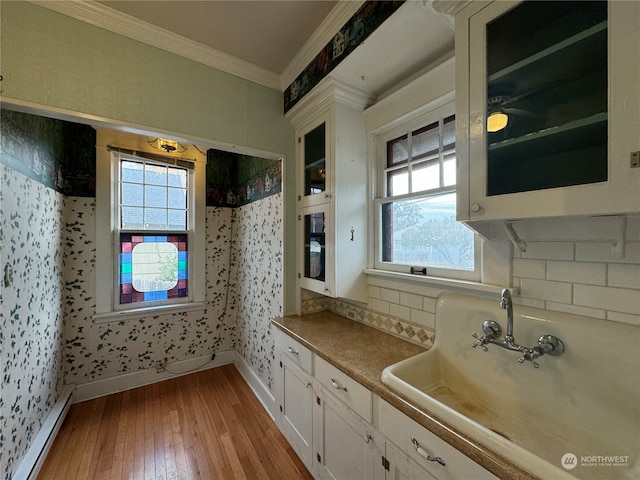 kitchen featuring crown molding, plenty of natural light, light hardwood / wood-style floors, and white cabinets