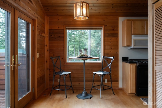 dining space featuring wooden ceiling, a chandelier, light wood-type flooring, and wooden walls