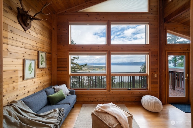 living room with light hardwood / wood-style flooring, wood walls, high vaulted ceiling, and wooden ceiling