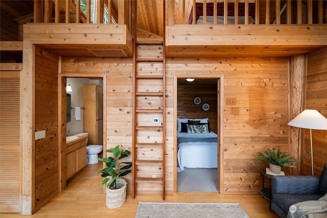 interior space with sink, light hardwood / wood-style flooring, and wooden walls