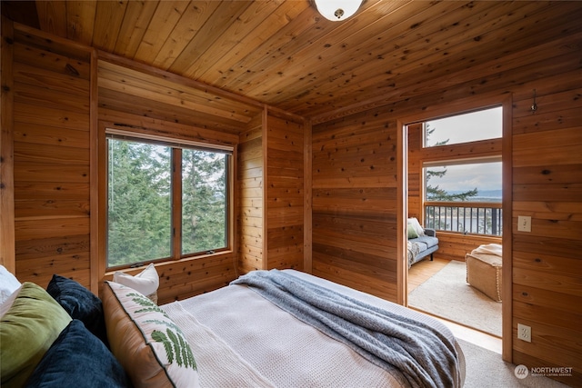 bedroom featuring light hardwood / wood-style flooring, multiple windows, access to outside, and wood walls