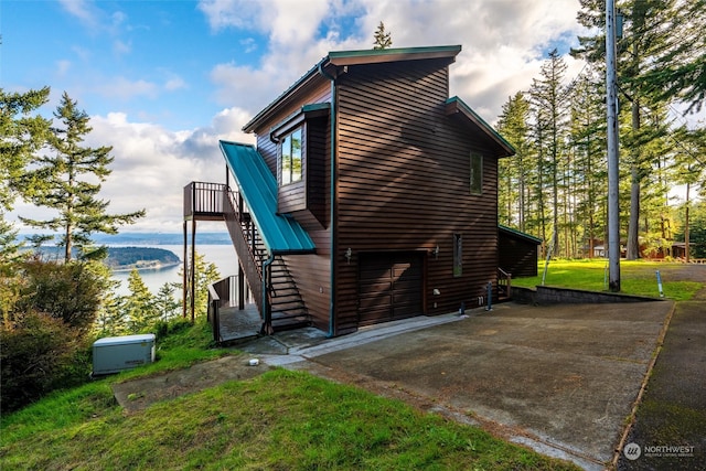 view of property exterior featuring a yard, a garage, and a water view