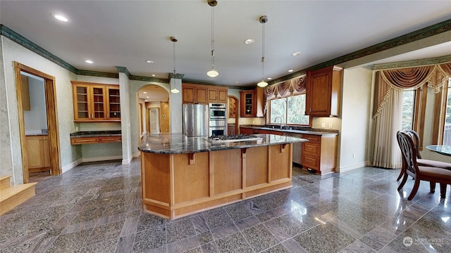 kitchen featuring appliances with stainless steel finishes, sink, a kitchen island, pendant lighting, and a breakfast bar area