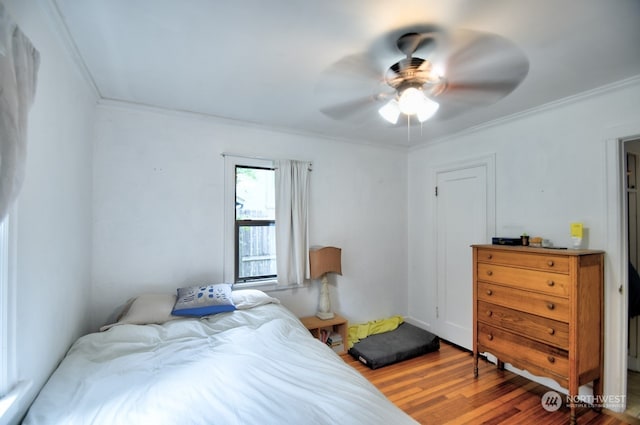 bedroom with ceiling fan, ornamental molding, and wood-type flooring