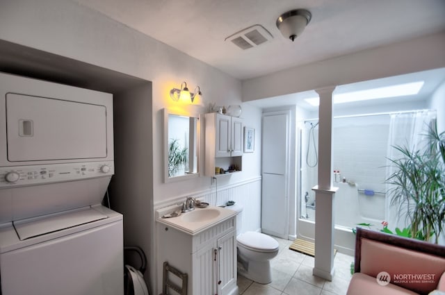 interior space featuring light tile patterned floors, sink, decorative columns, and stacked washer / drying machine