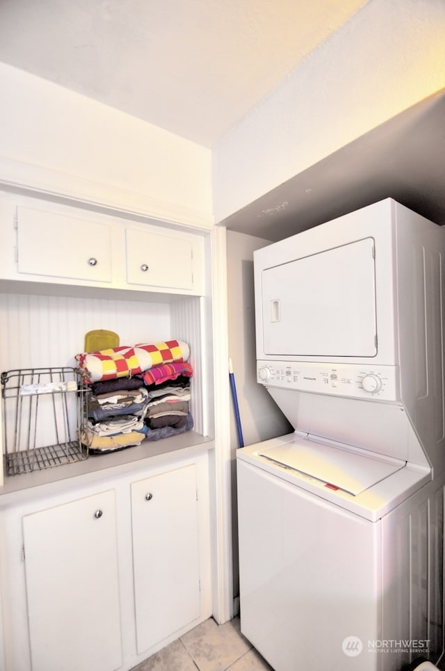 laundry room featuring stacked washer and clothes dryer and light tile patterned floors