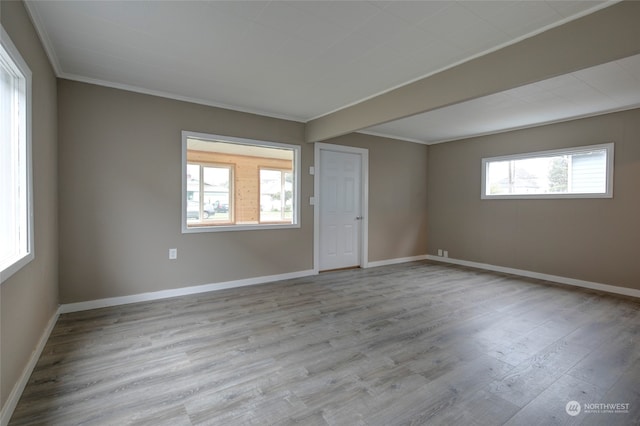 spare room featuring plenty of natural light, light hardwood / wood-style floors, and crown molding