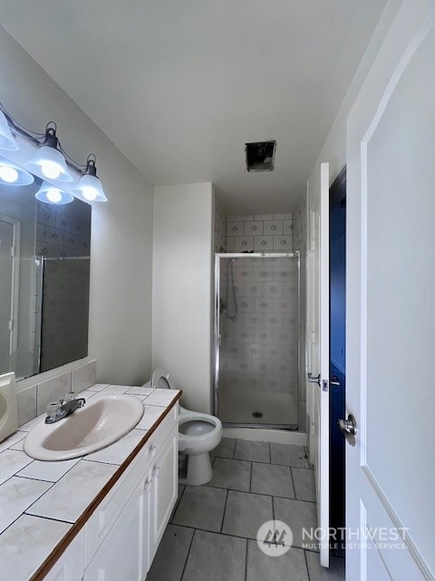 bathroom featuring vanity, tile patterned floors, toilet, and walk in shower