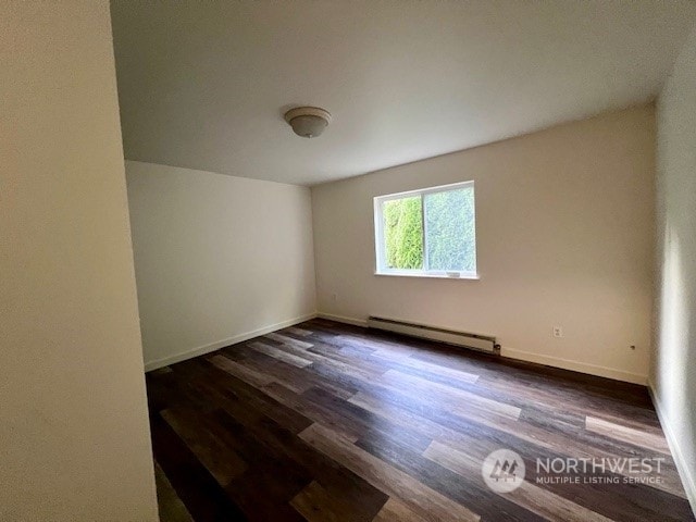 spare room with a baseboard radiator and dark wood-type flooring