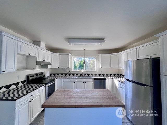 kitchen featuring appliances with stainless steel finishes, white cabinetry, butcher block counters, and light tile patterned floors