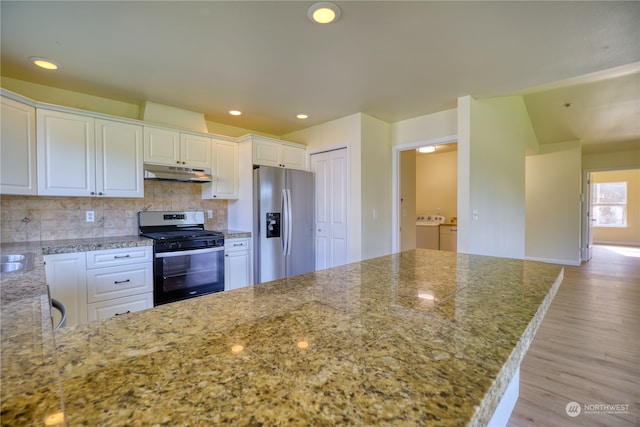 kitchen with light wood-type flooring, independent washer and dryer, white cabinetry, stainless steel appliances, and decorative backsplash