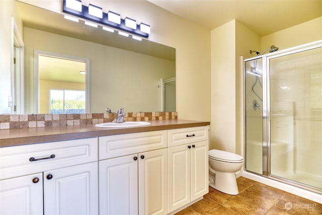 bathroom featuring vanity, toilet, tile patterned floors, and a shower with shower door