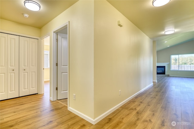 hall featuring vaulted ceiling and light hardwood / wood-style flooring