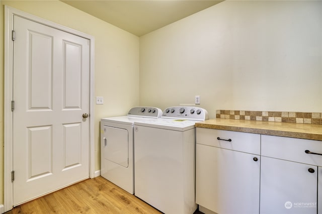 clothes washing area with washer and dryer, cabinets, and light hardwood / wood-style flooring