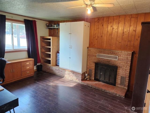 unfurnished living room featuring brick wall, dark hardwood / wood-style floors, wood walls, and ceiling fan