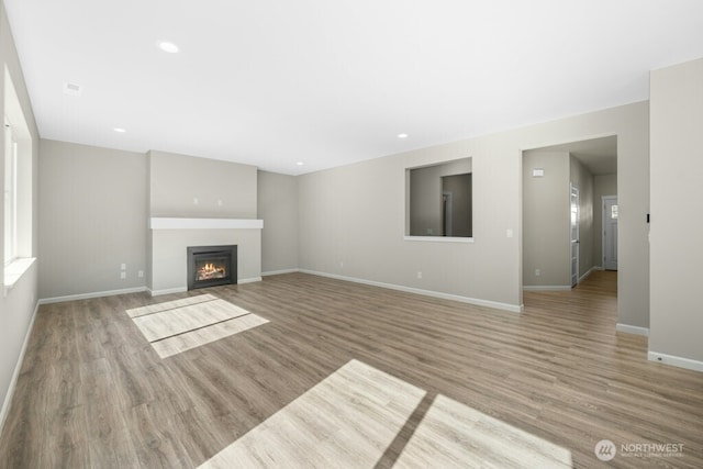 9865 Merrick St SE Unit 384, Yelm, WA 98597 - unfurnished living room featuring wood finished floors, a glass covered fireplace, and recessed lighting