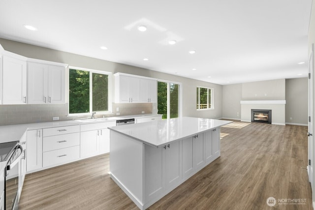 9865 Merrick St SE Unit 384, Yelm, WA 98597 - kitchen featuring stainless steel appliances, tasteful backsplash, a kitchen island, white cabinetry, and light wood finished floors