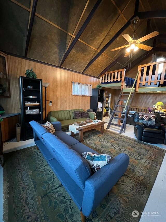 living room with wooden walls, high vaulted ceiling, and ceiling fan