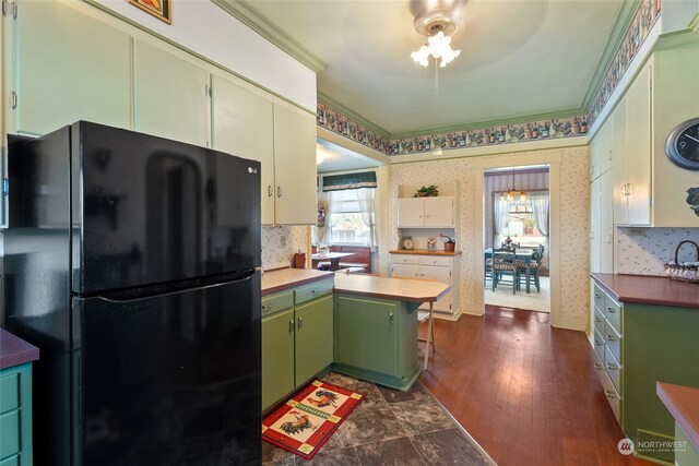 kitchen featuring dark wood-type flooring, ornamental molding, green cabinets, and black fridge