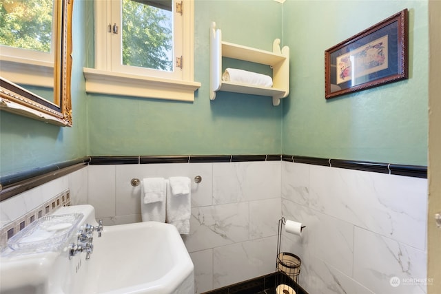 bathroom with tile walls, sink, and a healthy amount of sunlight