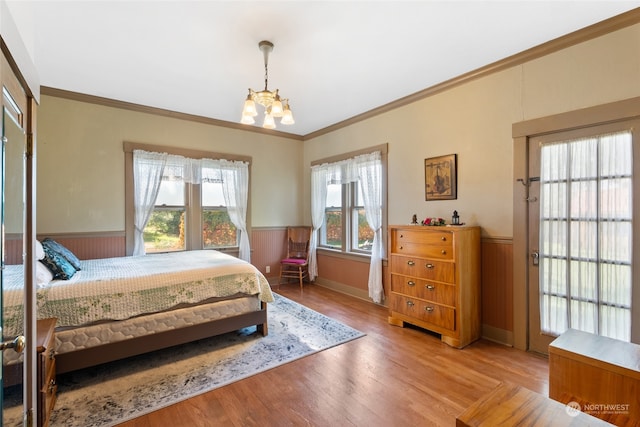 bedroom with an inviting chandelier, ornamental molding, and light hardwood / wood-style floors