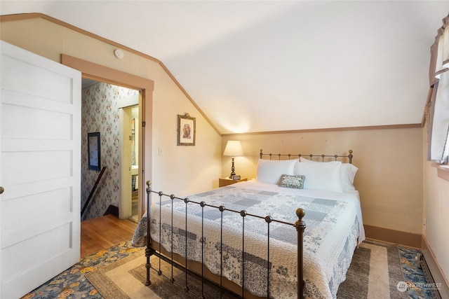 bedroom with lofted ceiling, crown molding, and hardwood / wood-style flooring