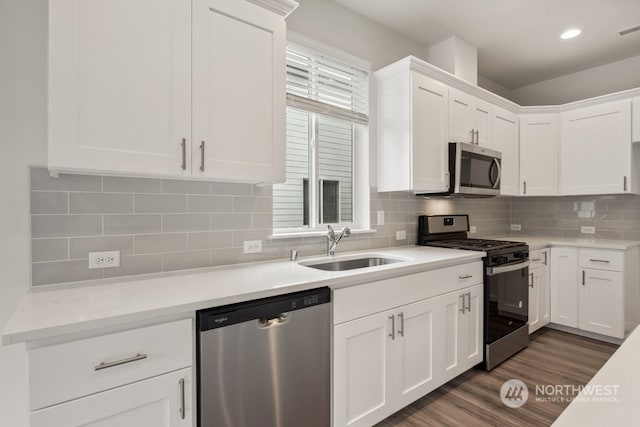 kitchen with white cabinets, sink, tasteful backsplash, dark wood-type flooring, and appliances with stainless steel finishes