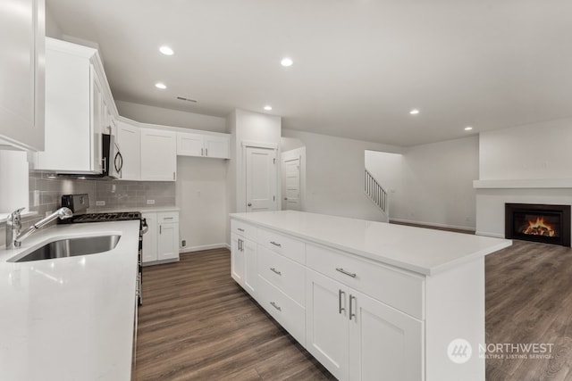 kitchen featuring dark hardwood / wood-style floors, appliances with stainless steel finishes, a center island, and white cabinetry