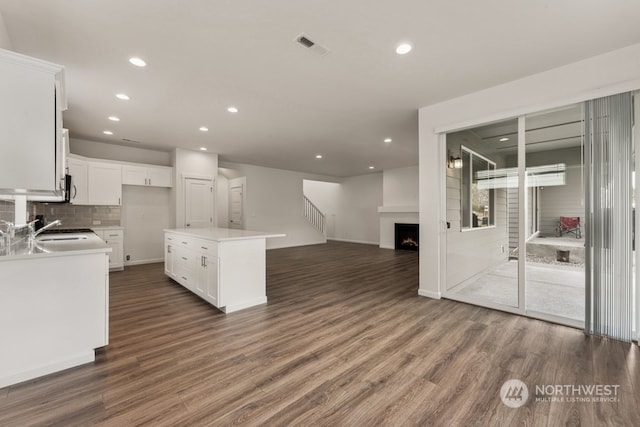 kitchen with white cabinets, backsplash, dark wood-type flooring, and a center island