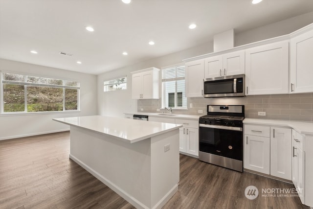 kitchen featuring a center island, white cabinets, dark wood-type flooring, sink, and appliances with stainless steel finishes