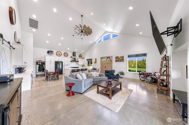 living room with a barn door, baseboards, visible vents, light speckled floor, and high vaulted ceiling