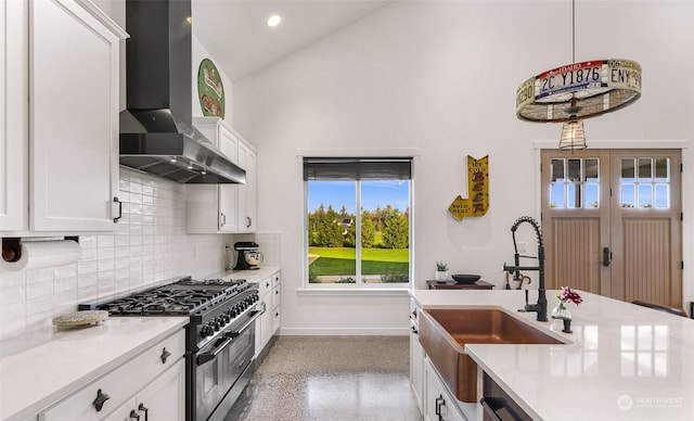 kitchen featuring a sink, wall chimney exhaust hood, light countertops, speckled floor, and double oven range