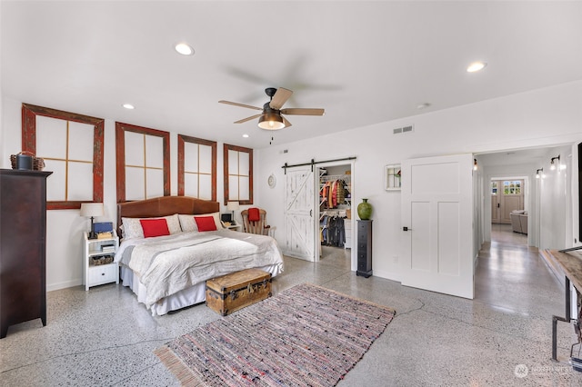 bedroom featuring a closet, a walk in closet, a barn door, and ceiling fan