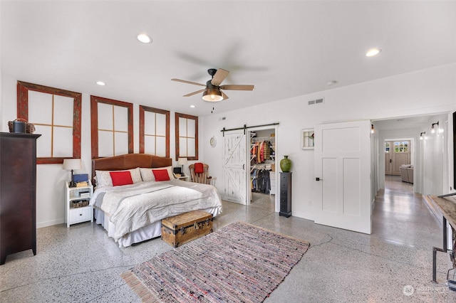 bedroom with speckled floor, visible vents, a barn door, and baseboards