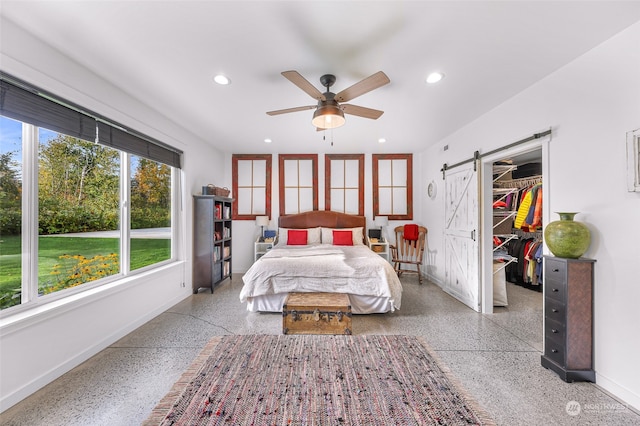 bedroom with a spacious closet, a barn door, a closet, and ceiling fan