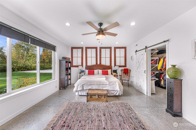bedroom with baseboards, a spacious closet, a barn door, and speckled floor