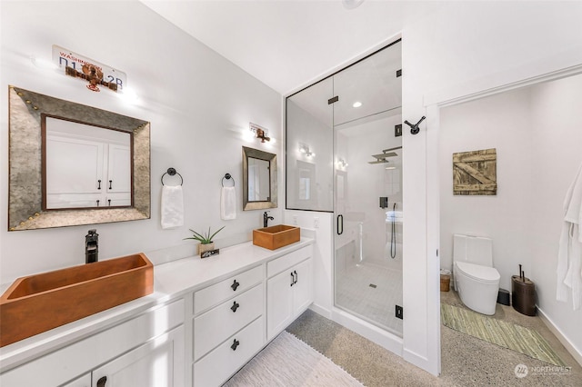 bathroom with a sink, double vanity, a shower stall, and speckled floor