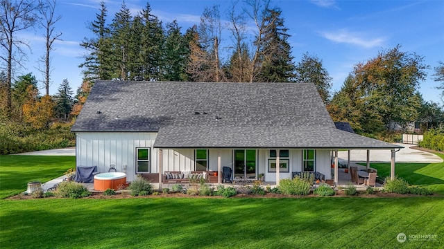 back of property featuring a porch, a lawn, roof with shingles, and board and batten siding