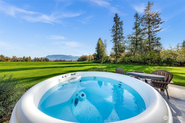 view of pool with a mountain view, a yard, and a hot tub